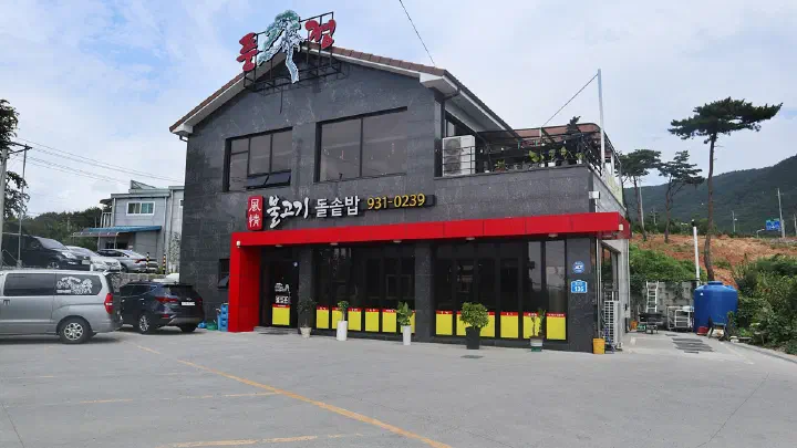 Exterior of Pungjeong Bulgogi in Boryeong, a standalone building with red accents and a wide parking lot