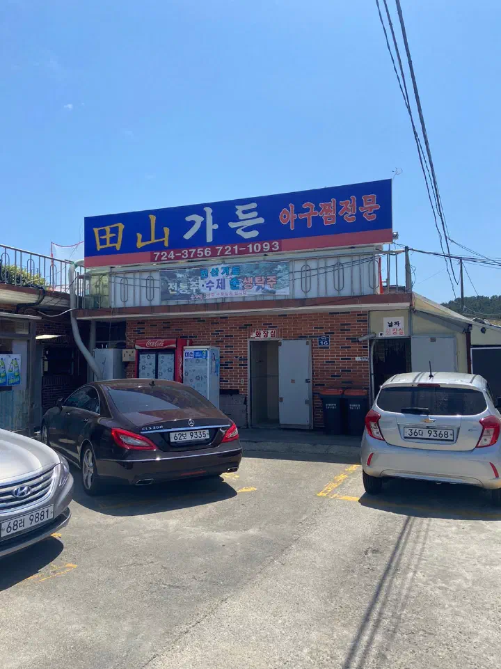 Exterior and blue signboard of Jeonsan Garden, a monkfish restaurant in Hangni village, Gijang, Busan