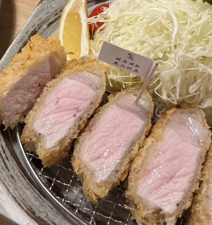 Cross-section of the charcoal-smoked Berkshire K roskatsu at Tonshou Gwangan showing a faint pink blush, served with shredded cabbage