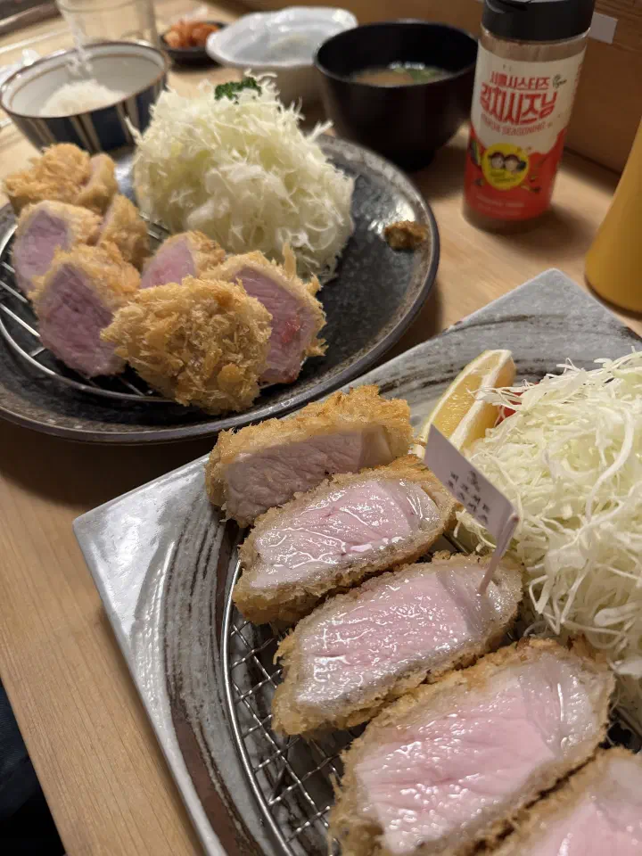 Two plates of hirekatsu and Berkshire K roskatsu side by side at Tonshou Gwangan with kimchi seasoning on the counter