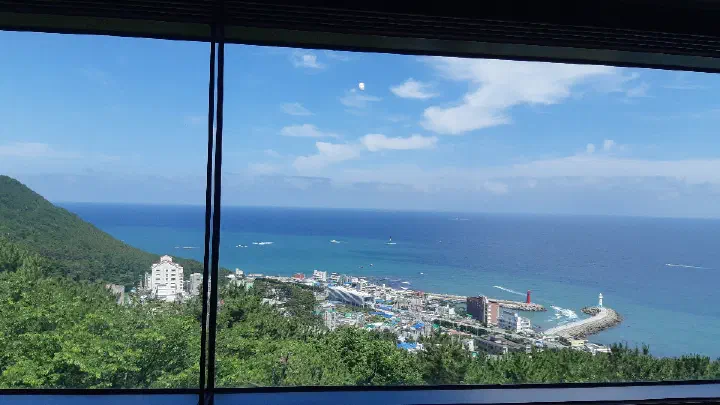 View of Cheongsapo village, the white lighthouse, and the sea through Bibibidang&rsquo;s window