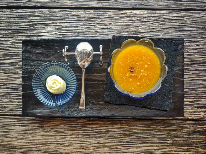 Sweet pumpkin sikhye rice punch in a glass bowl with a rice cake on the side