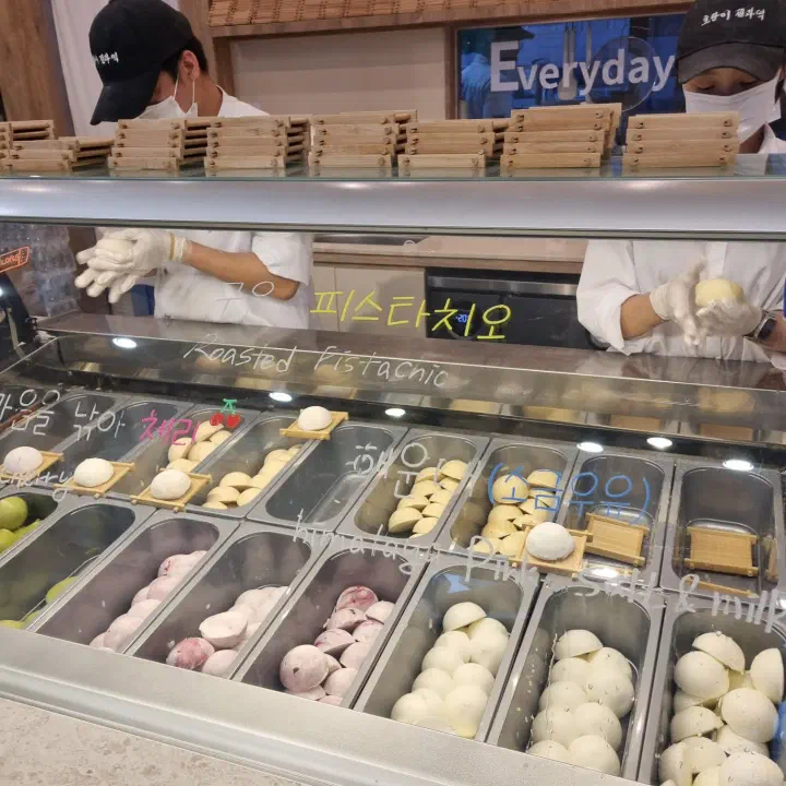 Staff shaping gelato-filled rice cakes behind the flavor display case at Horangi Jella Tteok