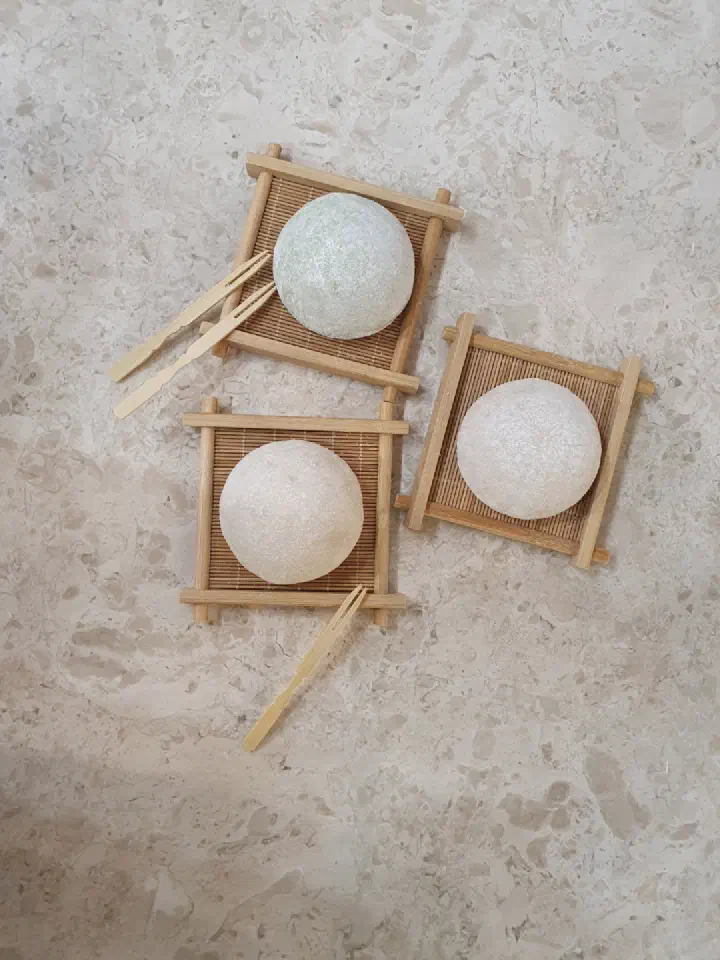 Top-down view of three gelato-filled rice cakes resting on small bamboo trays