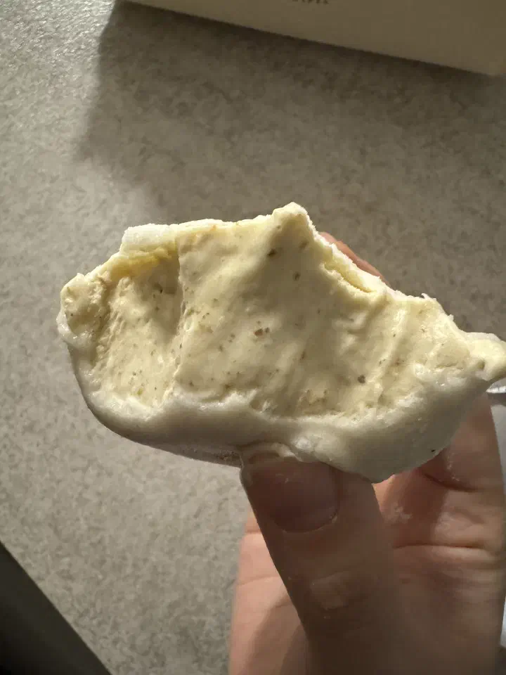 Cross-section of a roasted pistachio jella tteok bitten open to show the dense pistachio gelato inside