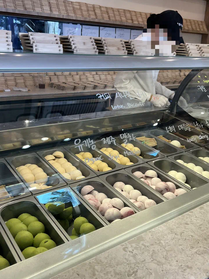 Display case at Horangi Jella Tteok showing organic Jeju matcha, strawberry, and salted milk gelato rice cakes by flavor
