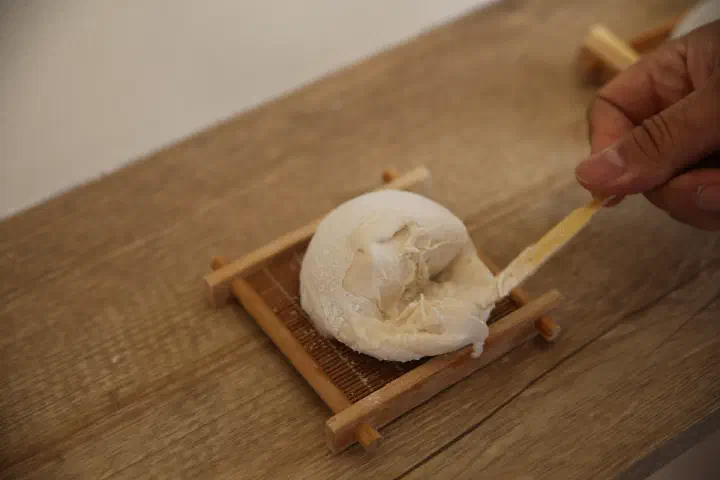 A softened jella tteok being scooped with a wooden spoon, the gelato spreading out smoothly