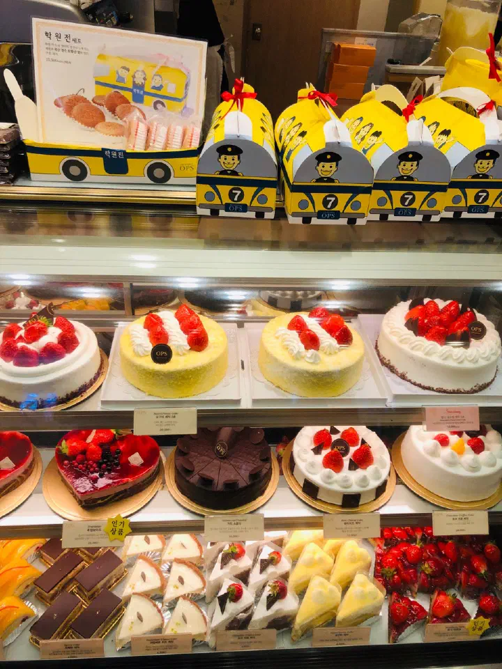 Cake showcase at OPS Haeundae with yellow school bus shaped hagwonjeon gift boxes on top