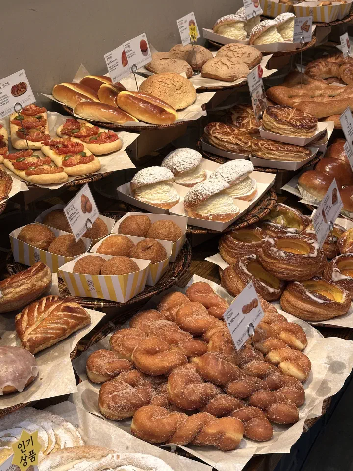 Cream-filled buns, sugared twist doughnuts and danishes on the display tables at OPS Haeundae bakery