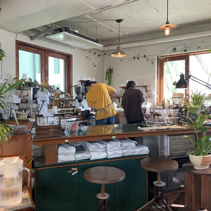 Barista pulling ristretto shots behind the espresso bar at Awluk, with bags of house-roasted beans stacked below