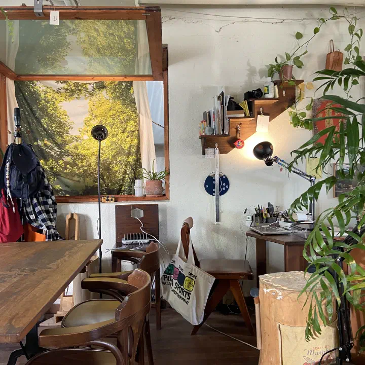 Plant-filled interior of Awluk cafe with the owner’s leather workbench in the corner