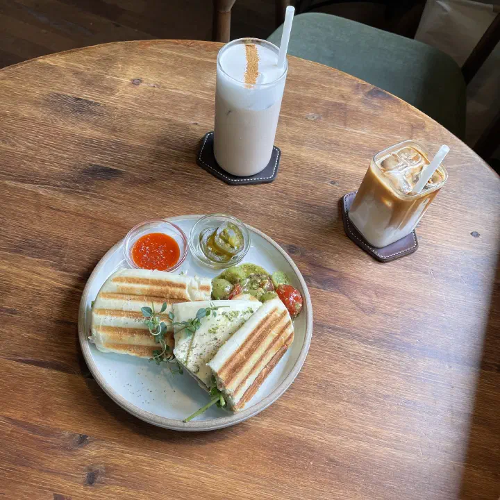 Signature Awluk coffee and an iced latte served with a panini sandwich plate at Awluk cafe