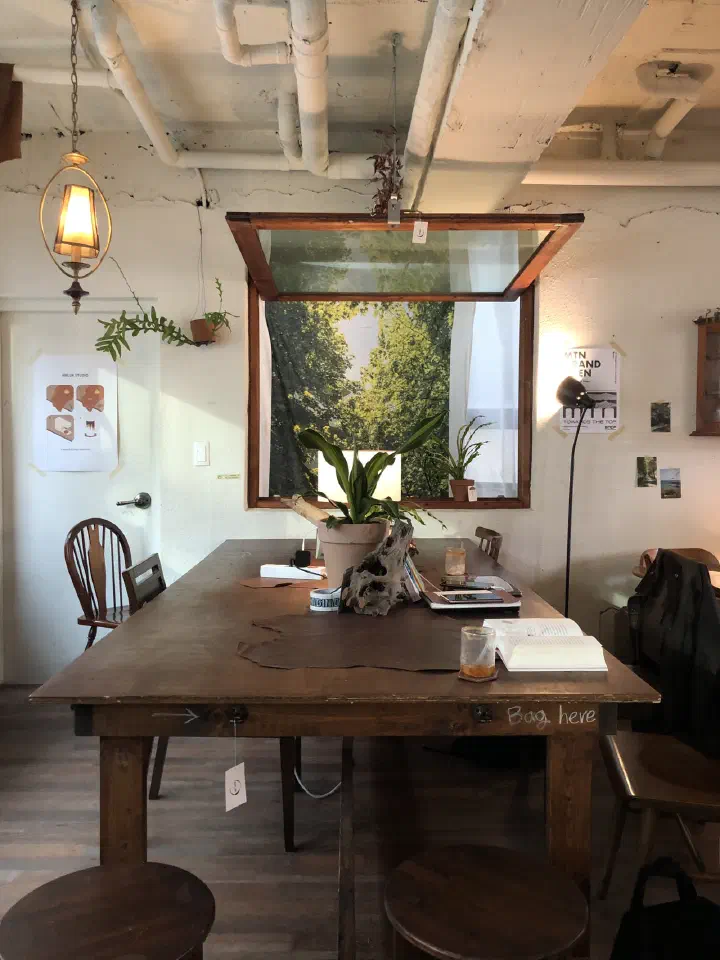 Large wooden table by the window at Awluk cafe in Jeonpo, Busan, with a forest photo hung in the window frame