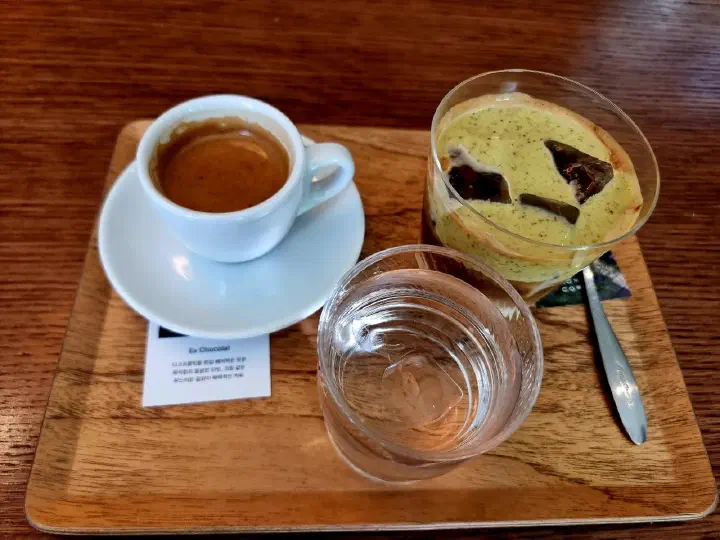Momos Coffee espresso and the signature Modeuui Jeongwon latte topped with pistachio cream on a wooden tray