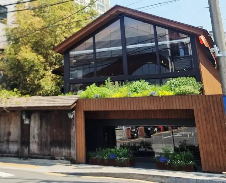 Exterior of Momos Coffee Flagship Store in Busan, a gabled glass building above a traditional tiled gate