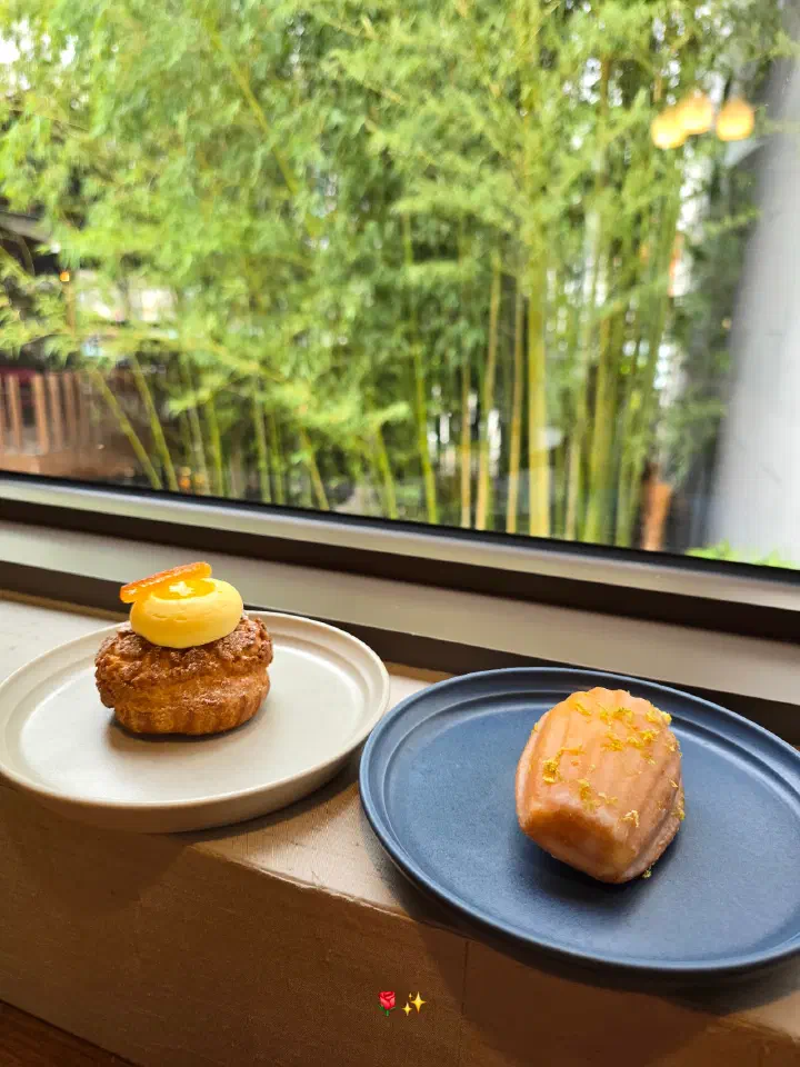 Lemon-lime madeleine and yuja cream dessert on a windowsill overlooking bamboo at Momos Coffee