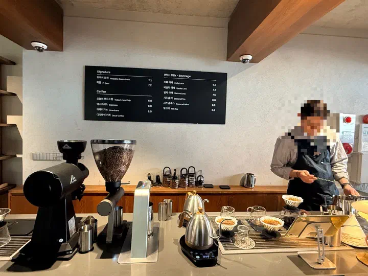 Order counter and menu board at Momos Coffee Busan showing Today&rsquo;s Hand Drip and signature drink prices