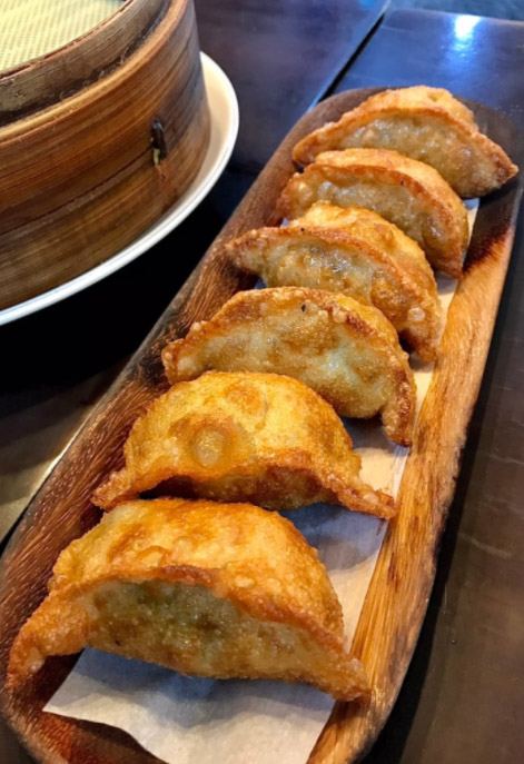 Close-up of golden crispy fried dumplings lined up on a wooden plate at Sinbalwon in Busan
