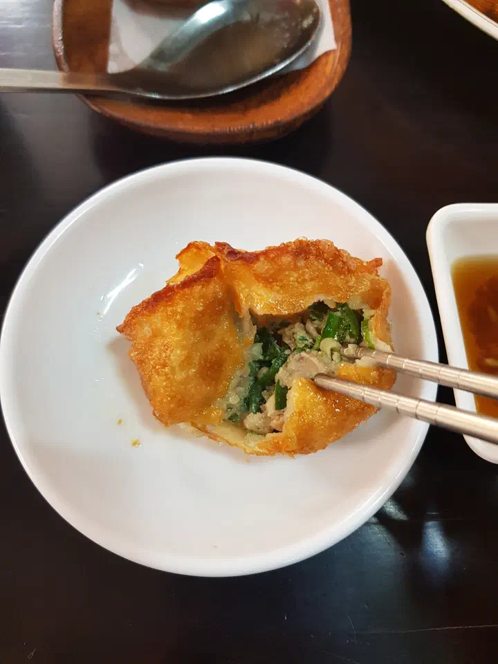 Fried dumpling torn open at Sinbalwon revealing the juicy pork and chive filling inside