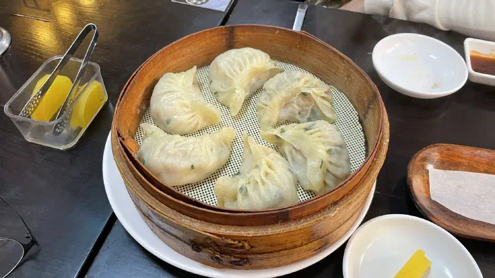 Six steamed pork dumplings with fermented dough wrappers served in a bamboo steamer at Sinbalwon