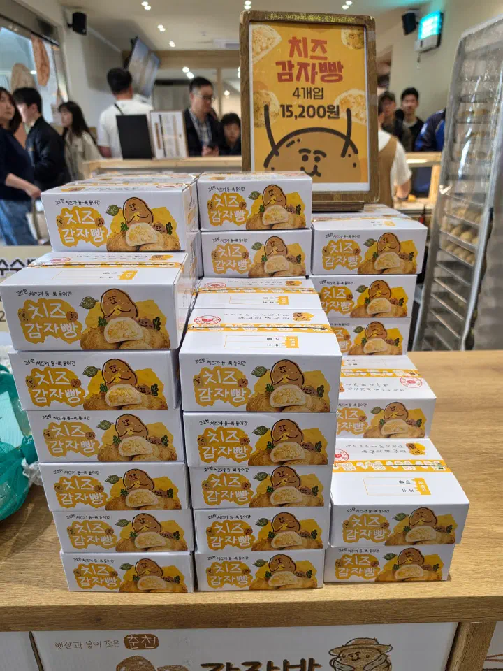 Stacked boxes of cheese potato bread, four pieces per box, at Gamzabatt in Chuncheon