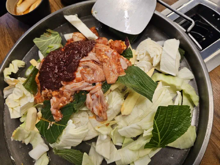 통나무집닭갈비 본점 철판 위 깻잎과 양배추, 고구마채가 함께 올라간 조리 전 닭갈비