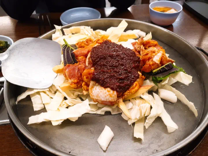 통나무집닭갈비 본점의 조리 전 철판에 올라간 당일 손질 닭다리살과 양배추, 고구마