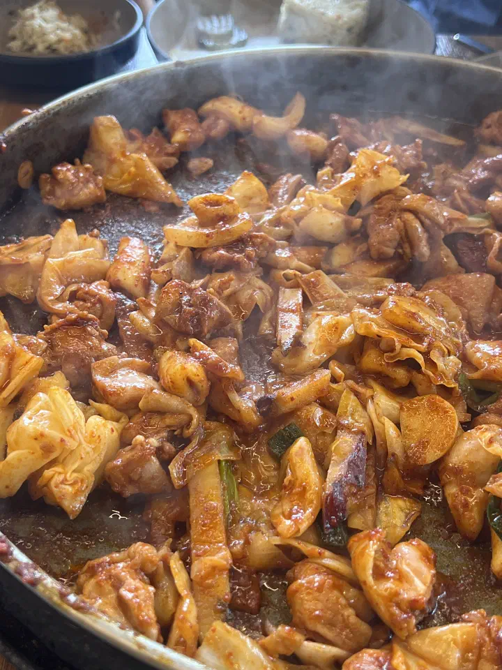 통나무집닭갈비 본점 철판에서 볶아지는 중인 닭갈비와 양배추, 대파
