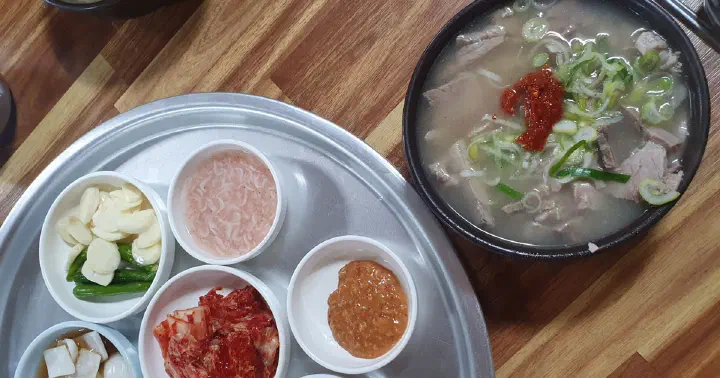 A tray of banchan - garlic, salted shrimp, kimchi - with a bowl of gukbap