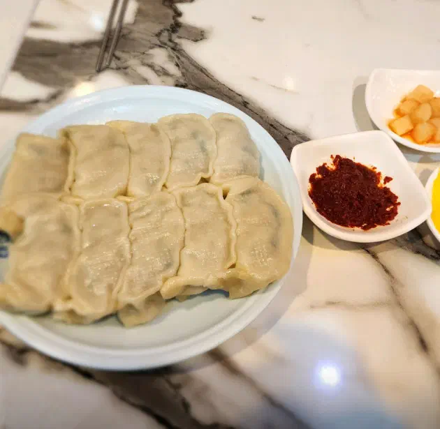 Taesan Mandu steamed jjin-mandu (jjingyoseu) with a chewy wrapper, served with a dish of seasoned chili paste
