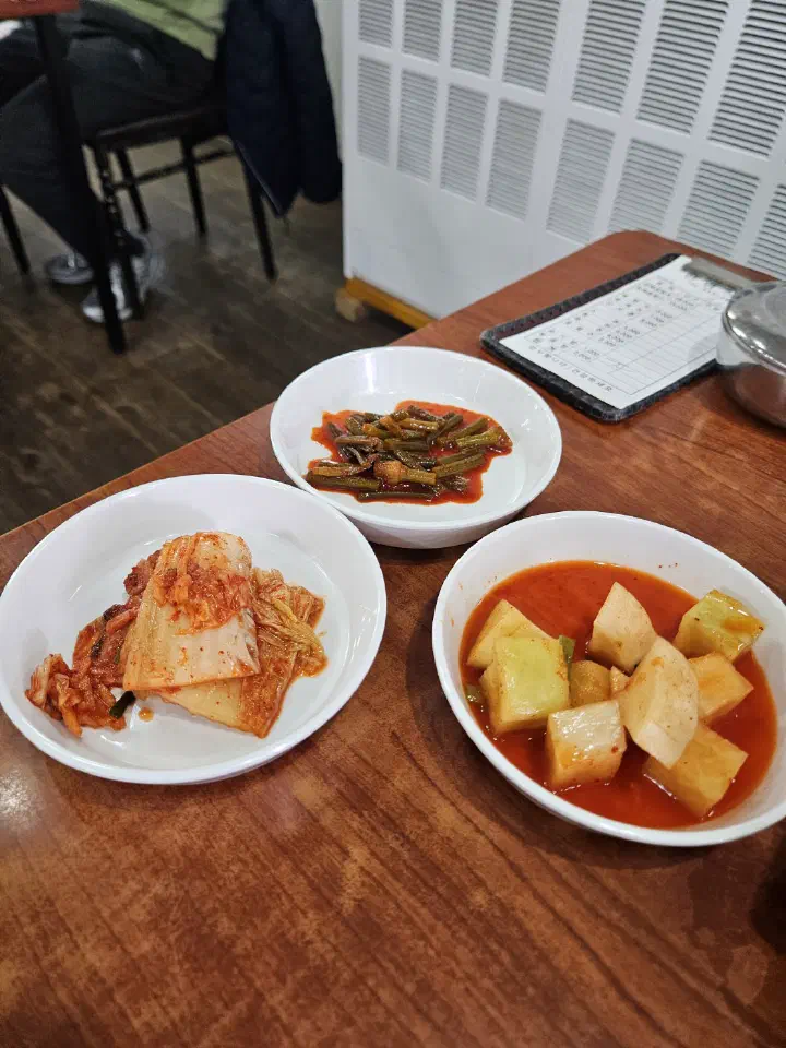 Banchan side dishes at Hanyeong Sikdang: kimchi, stir-fried sweet potato stems and radish water kimchi