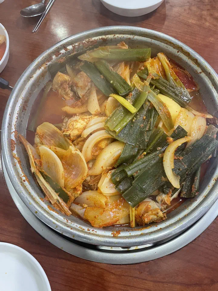 Uncooked dak-bokkeumtang pot piled with raw chicken, scallions and onions at Hanyeong Sikdang
