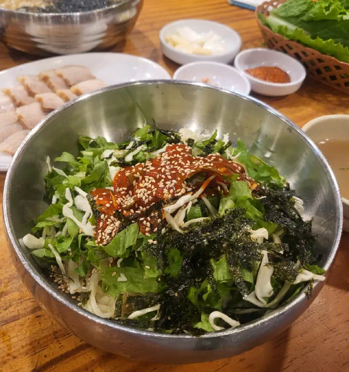 Bibimguksu at Kimhwa Kalguksu piled with shredded cabbage, lettuce and crumbled seaweed