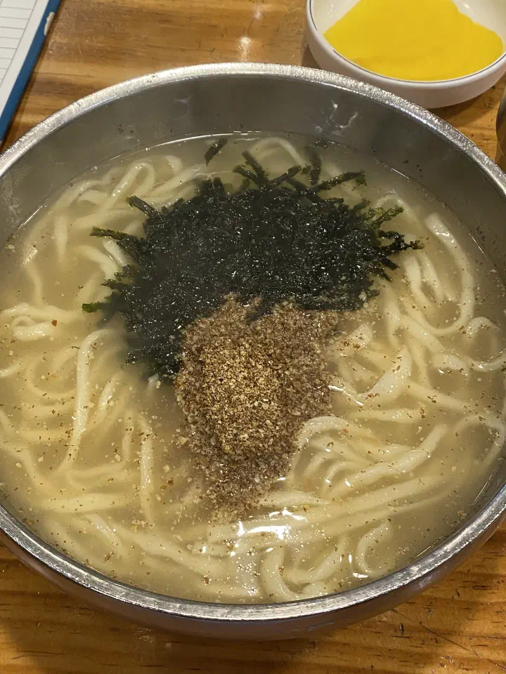 Deulkkae kalguksu topped with ground perilla seed and shredded seaweed over clear anchovy broth