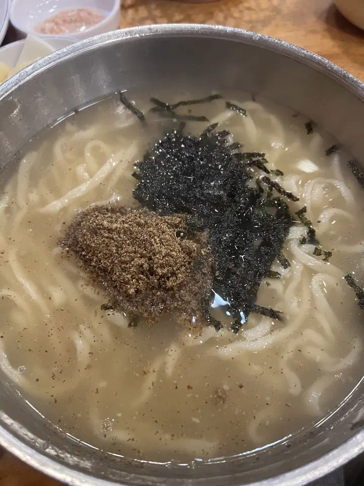 Uneven hand-cut kalguksu noodles filling a wide stainless steel bowl