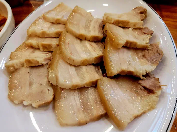 Close-up of tender boiled pork slices served at Kimhwa Kalguksu
