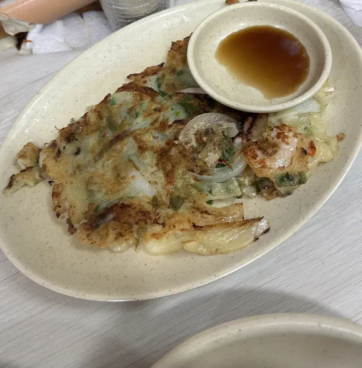 Close-up of OC Kalguksu haemul-pajeon showing squid and shrimp in a thick crispy pancake