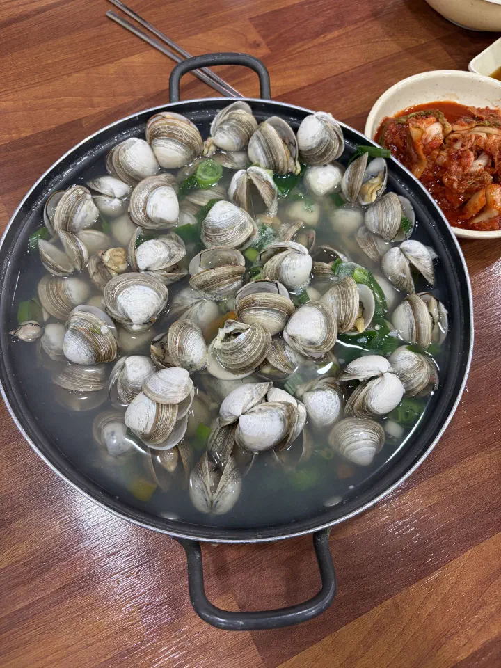 Close-up of OC Kalguksu mulchong, plump dongjuk clams in a clear savory broth