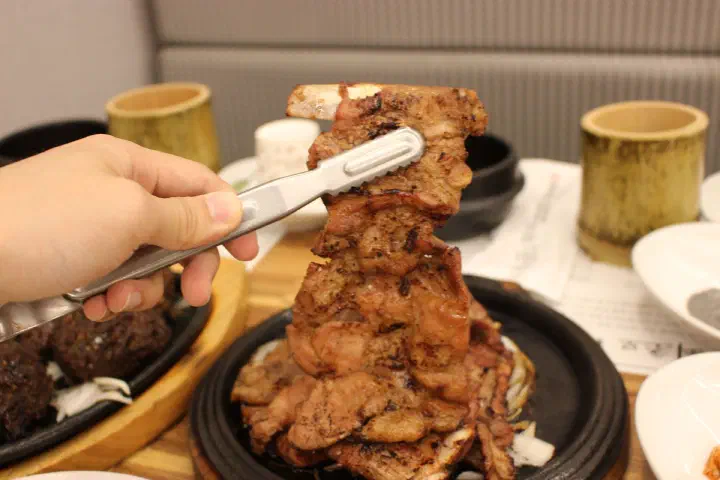 집게로 든 한상근대통밥집 돼지숯불갈비 클로즈업