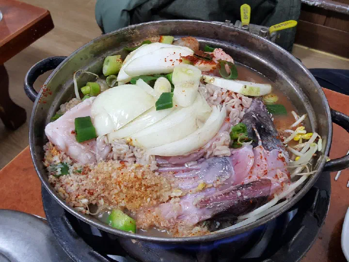 Raw monkfish, bean sprouts and minced garlic in a Samdado agutang pot before boiling at the table