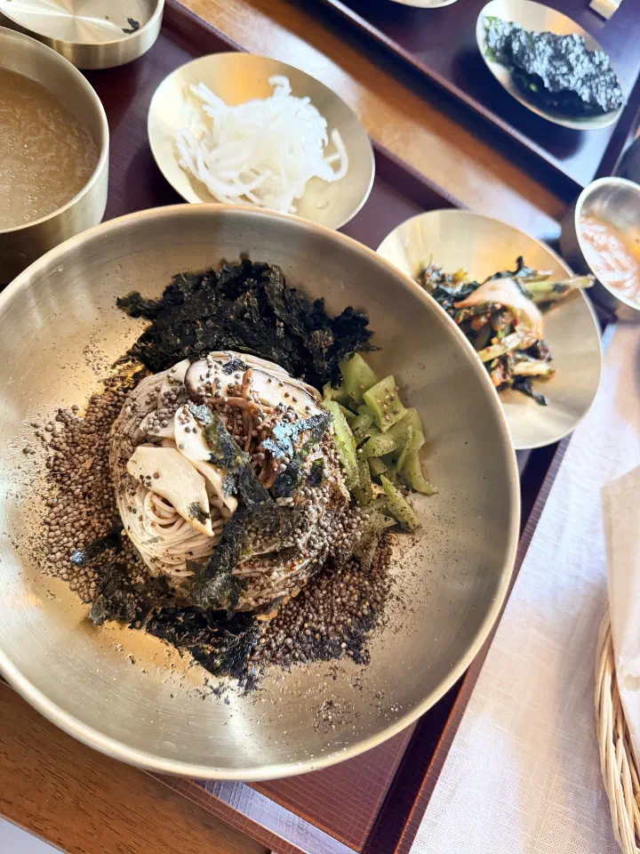 Close-up of house-cut buckwheat noodles topped with mushrooms, gungchae, seaweed and crushed perilla seed