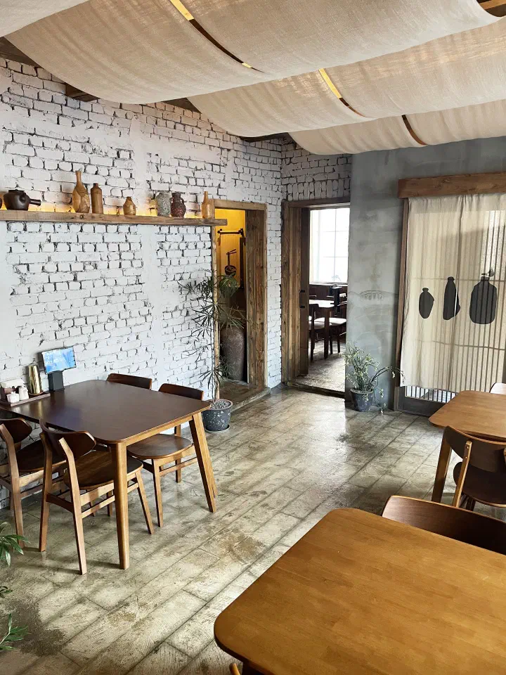Second floor dining room at Apgujeong Sanghoe with whitewashed brick walls and fabric draped across the ceiling