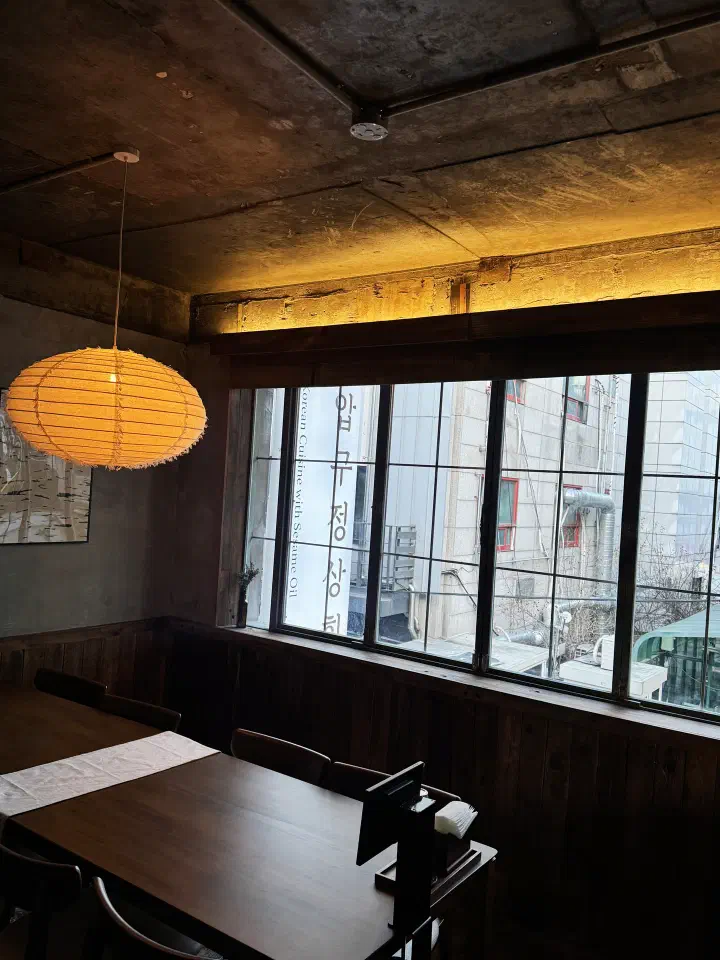 Window seat at Apgujeong Sanghoe with the restaurant&rsquo;s name and &ldquo;Korean Cuisine with Sesame Oil&rdquo; printed on the glass