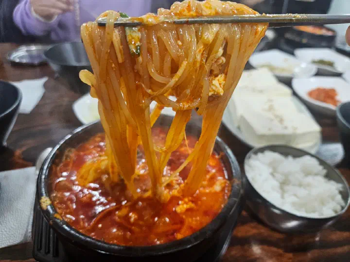 최일순짬뽕순두부 치즈쫄면순두부의 쫄면을 젓가락으로 들어 올린 모습