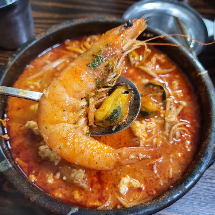 숟가락으로 건져 올린 최일순짬뽕순두부의 통새우와 홍합
