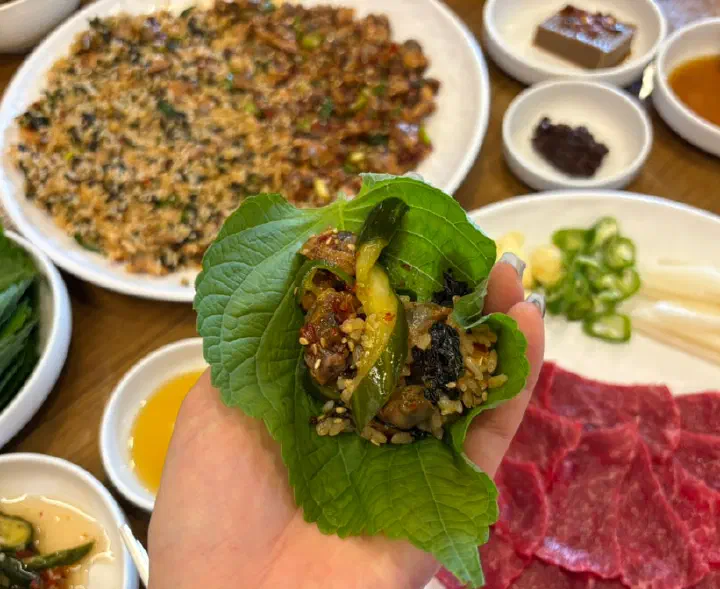 A perilla leaf wrap filled with cockle rice and seasoned cockles at Dokdone