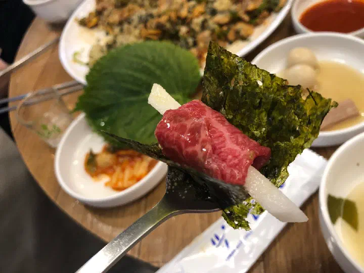 A slice of raw beef and Korean pear wrapped in roasted seaweed