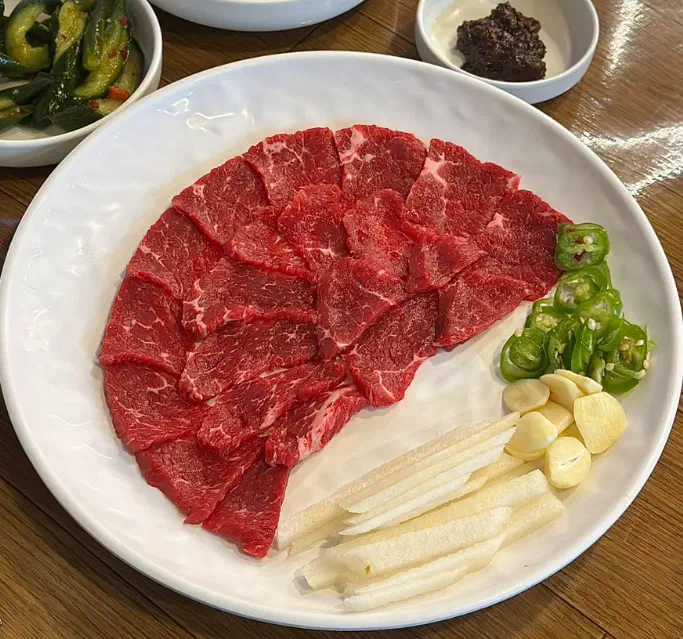 Plate of yuk sashimi raw beef slices with garlic, green chili and Korean pear at Dokdone
