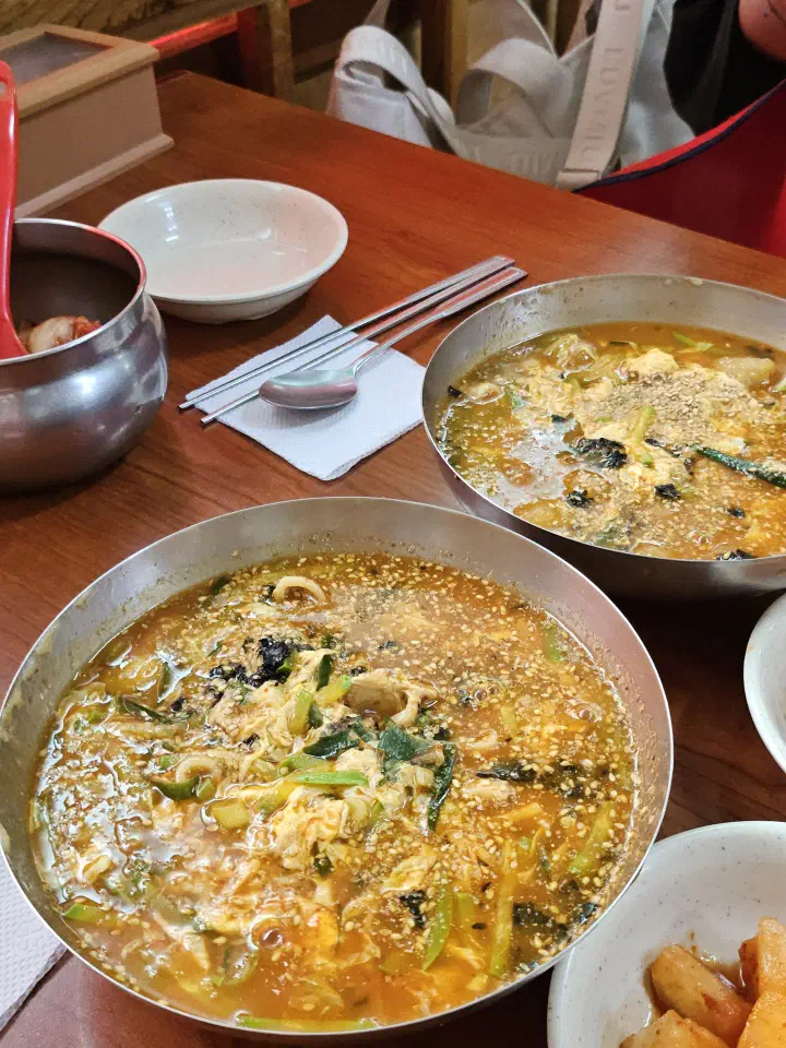 Two bowls of jang kalguksu served on a low wooden table at Geumcheon Kalguksu