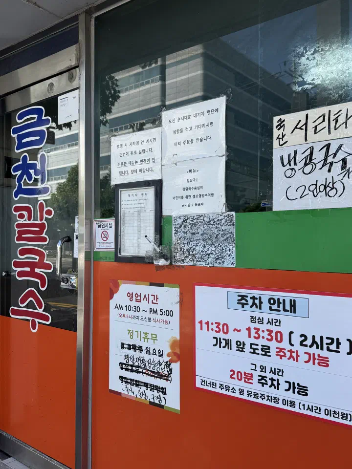 Paper waiting list and parking notice taped to the entrance window of Geumcheon Kalguksu